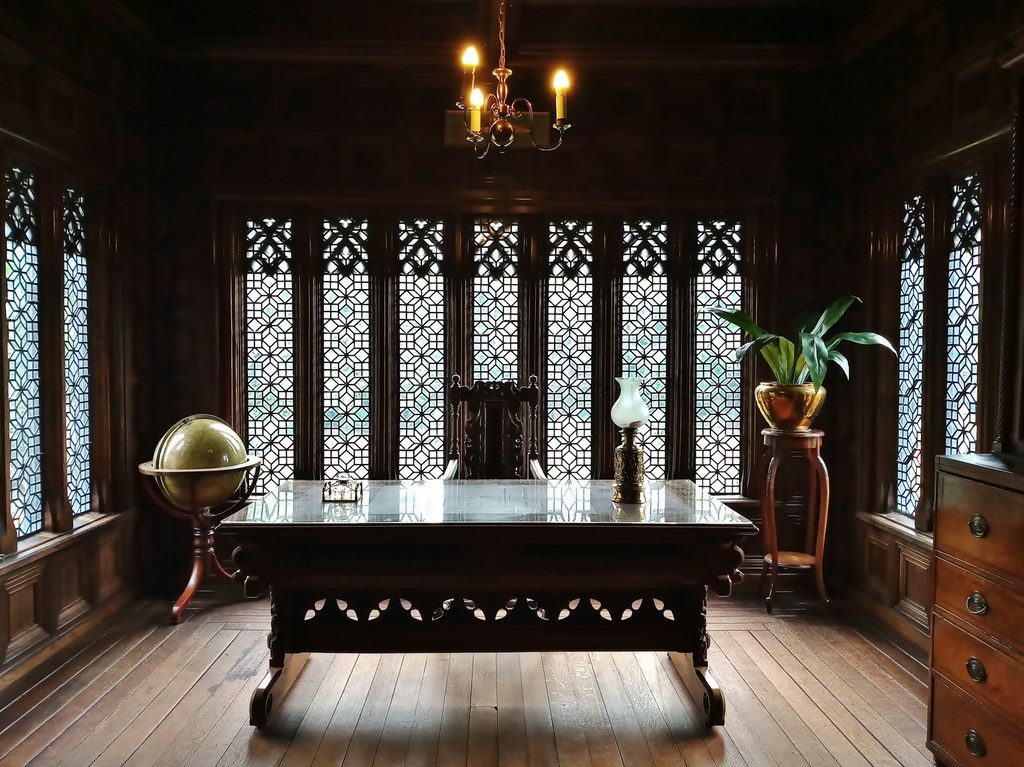 Luxurious victorian style home office with dark walls and chandelier