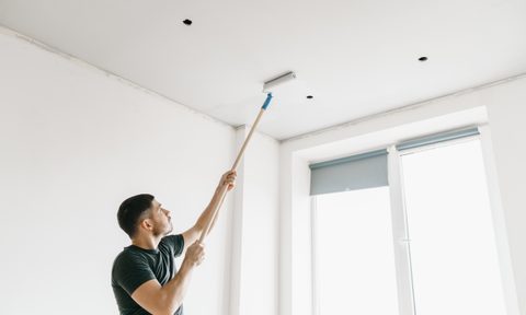 Man using a roller to paint the ceiling