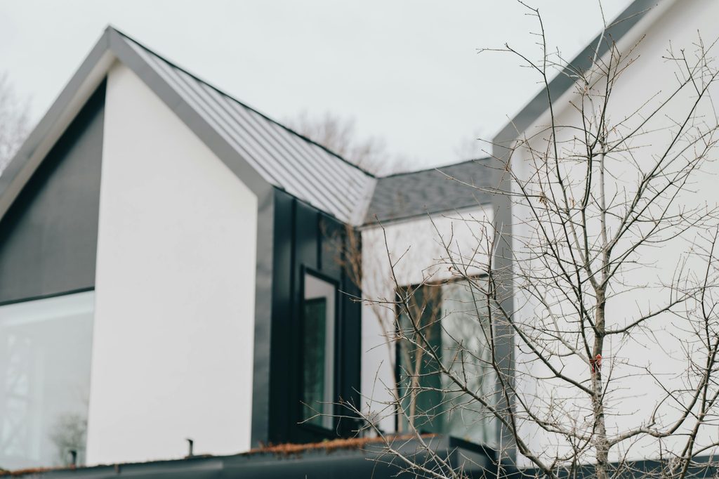 blurred house with metal roof with tree in foreground