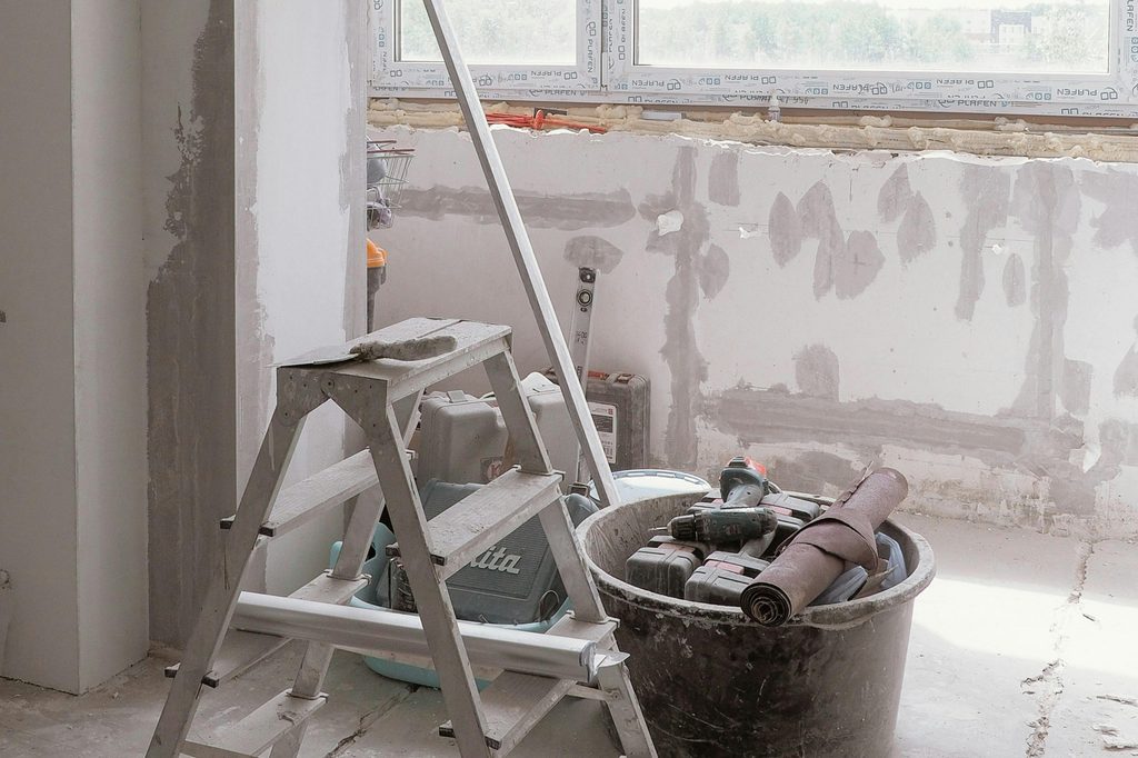 ladder and tools in front of patched drywall with spackle