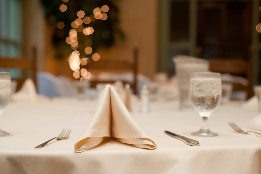 Formal dinner table with white tablecloth and folded napkins