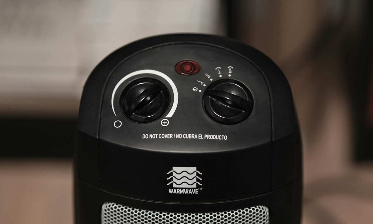 Black space heater with two knobs against unfocused background