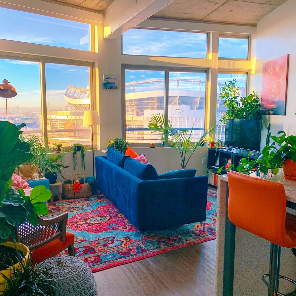 Boho-inspired living room with colorful area rug and lots of plants