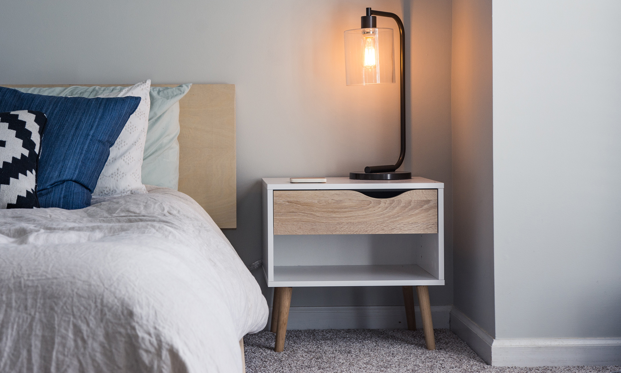 tall curved lamp on light wood bedside table