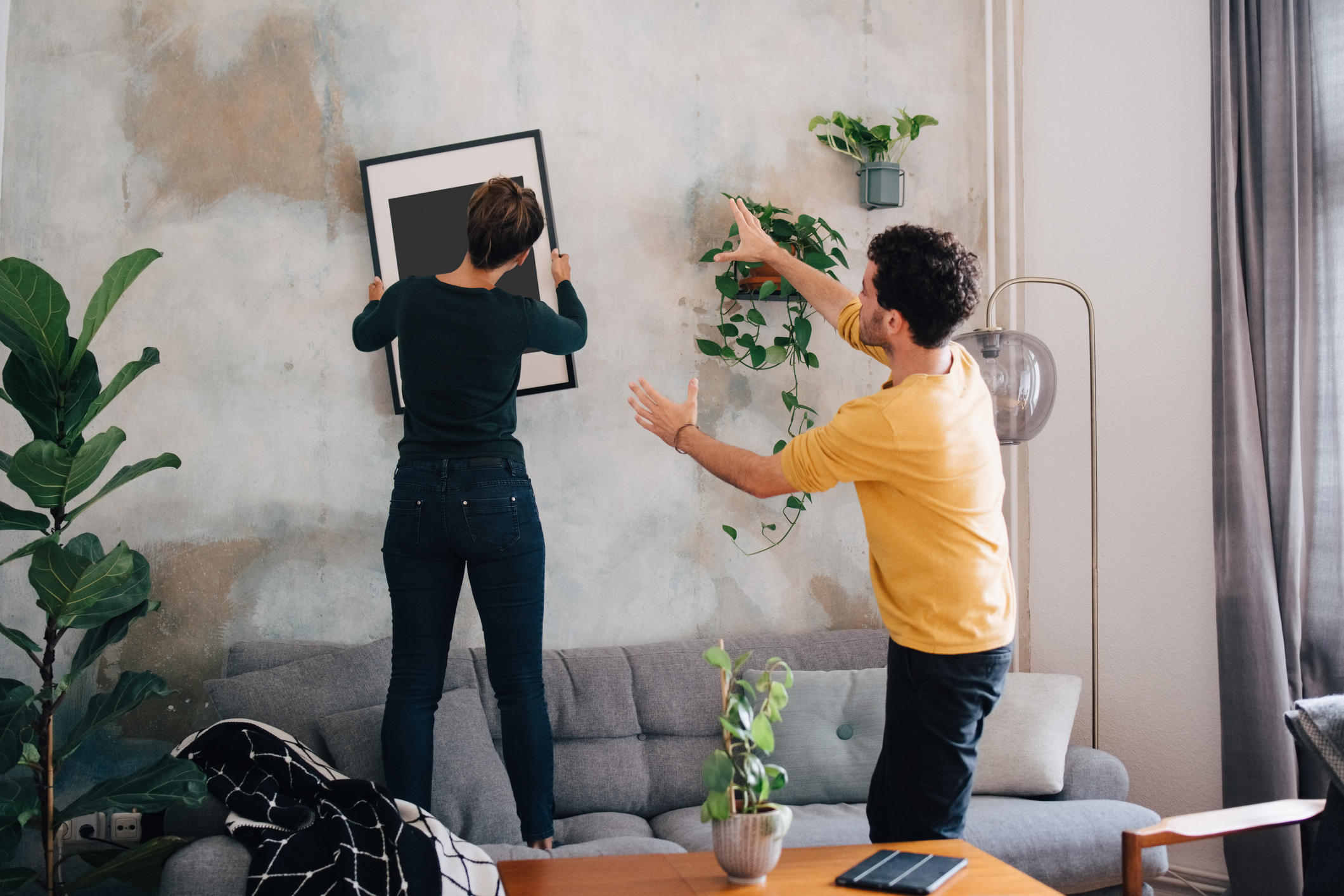 Two people hanging a picture on a wall