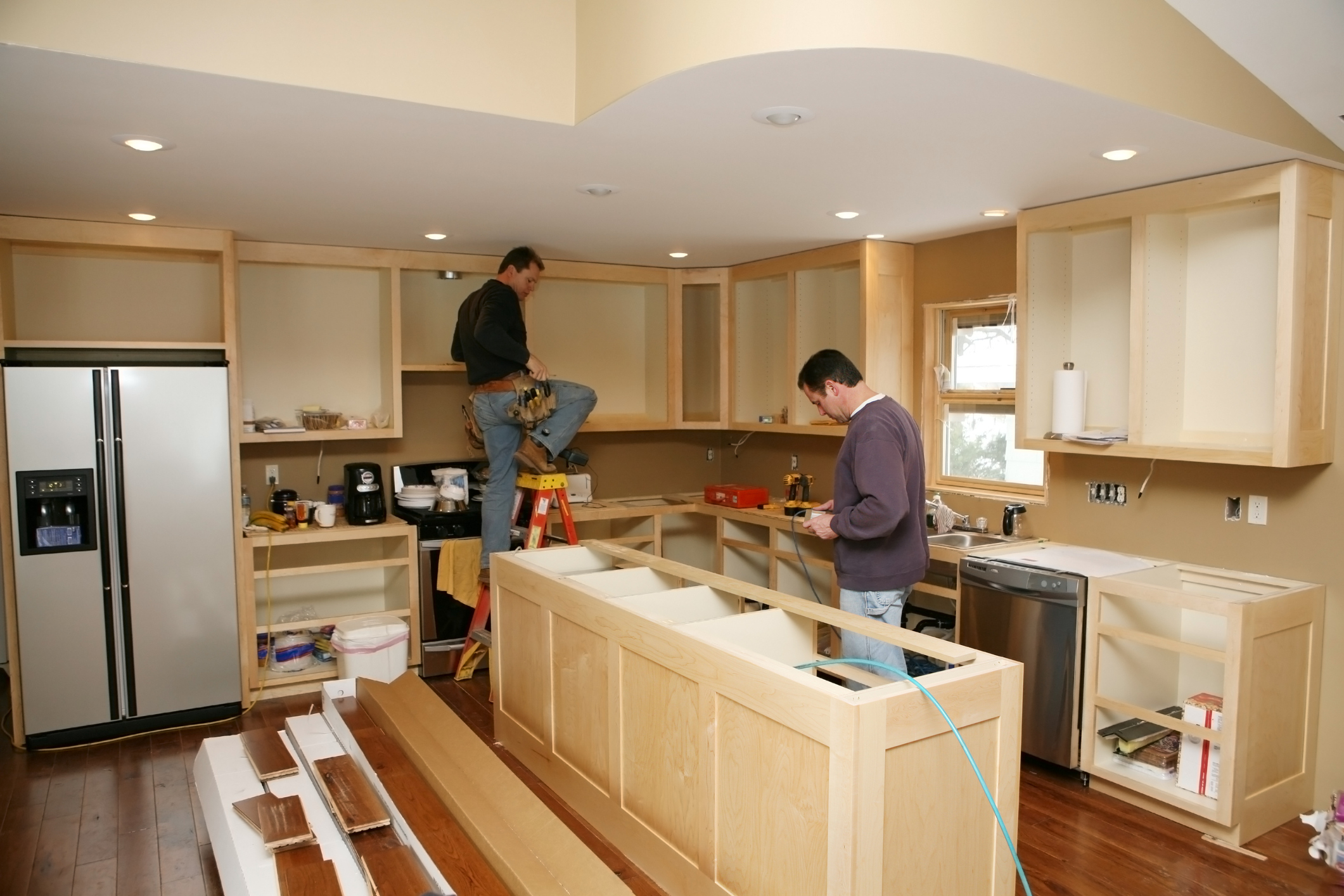 two people installing kitchen cabinets