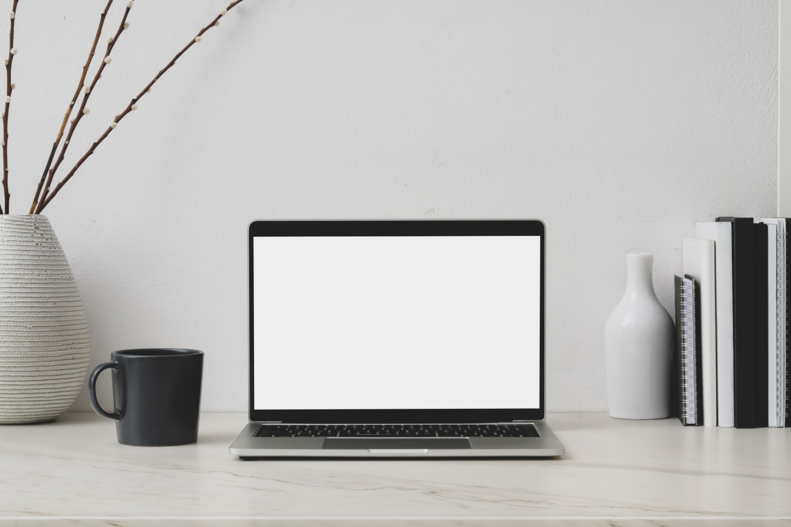 Laptop on desk with white wall
