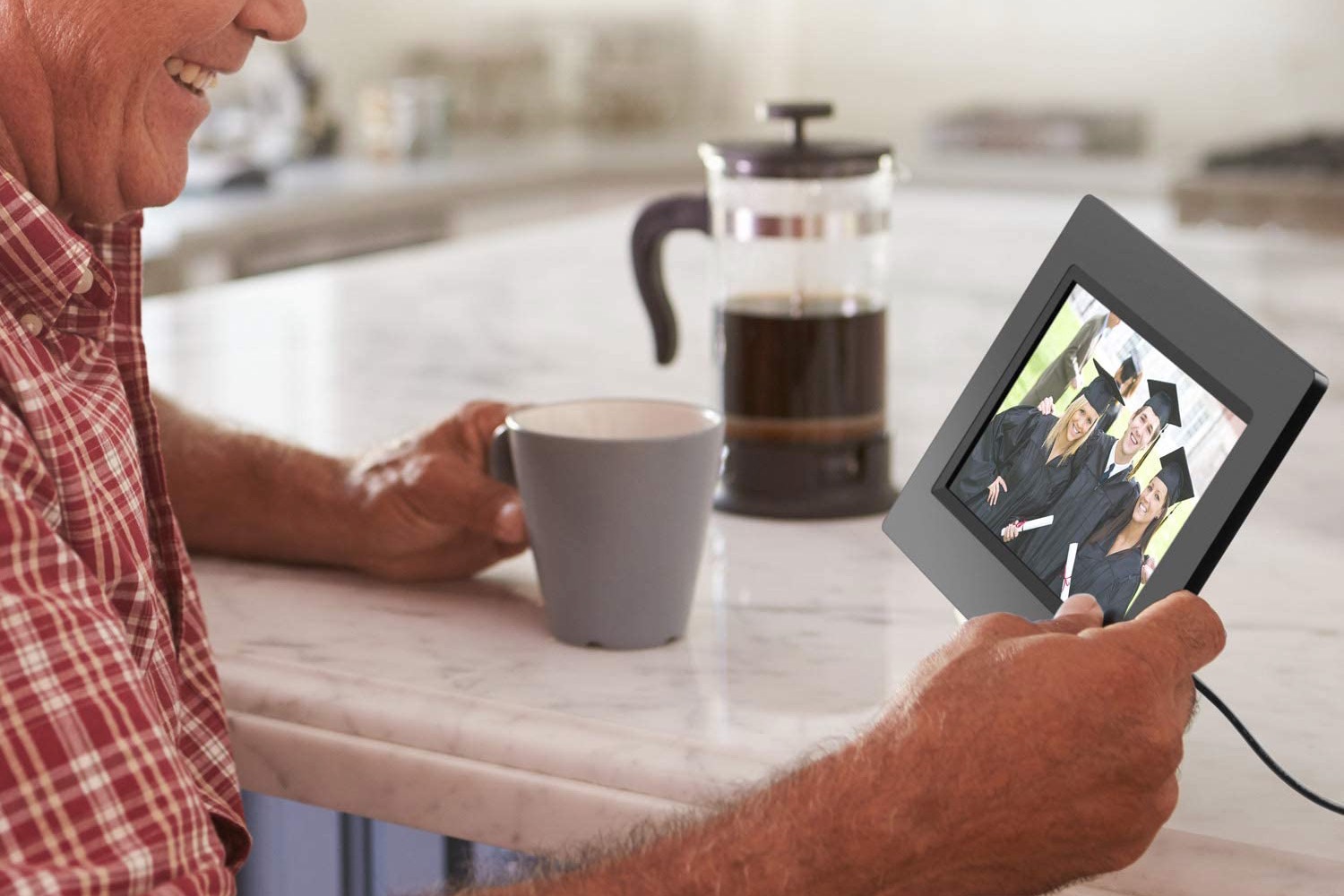 Man dirinking coffee and looking a digital photo frame