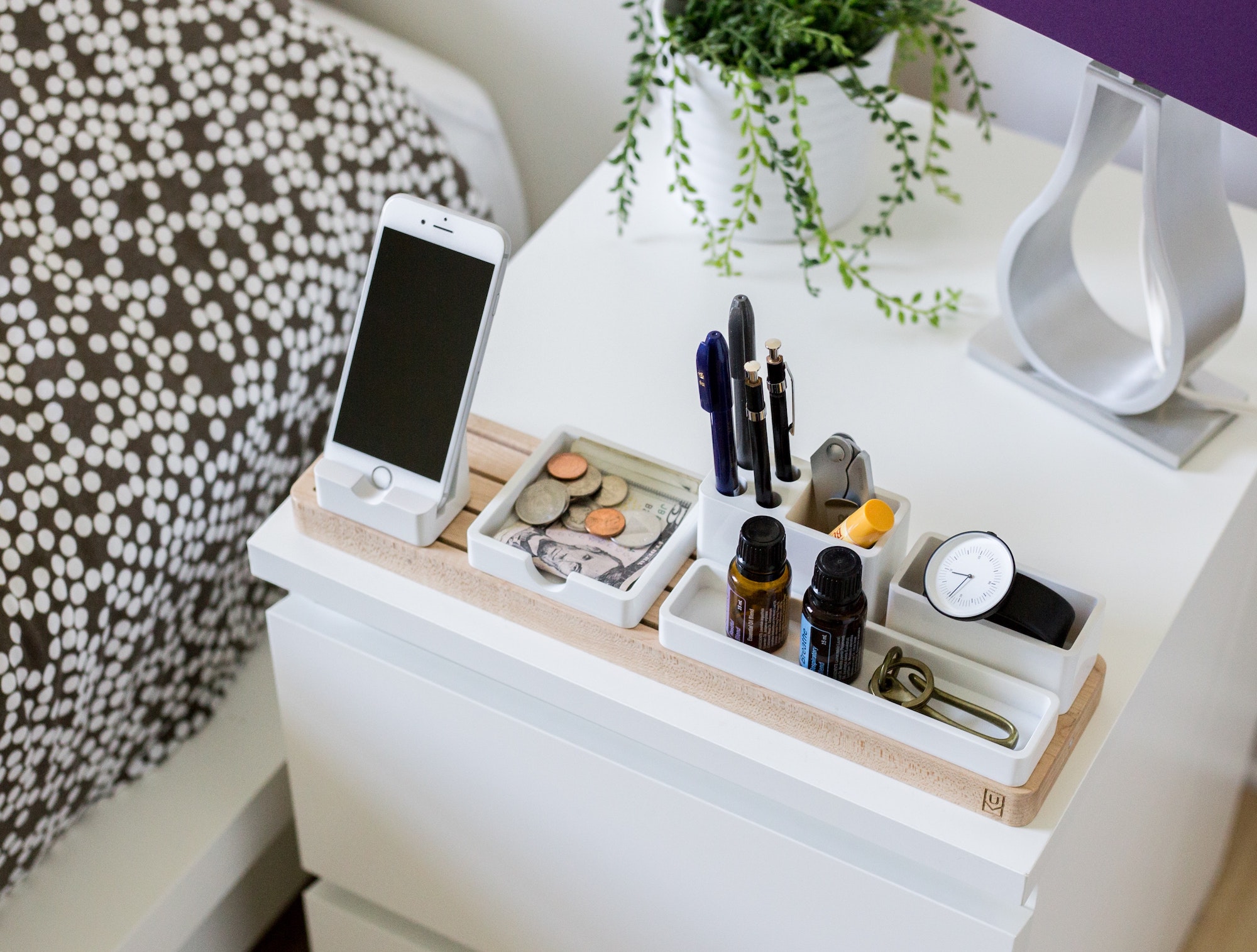 white cabinet with phone and makeup on top next to bed