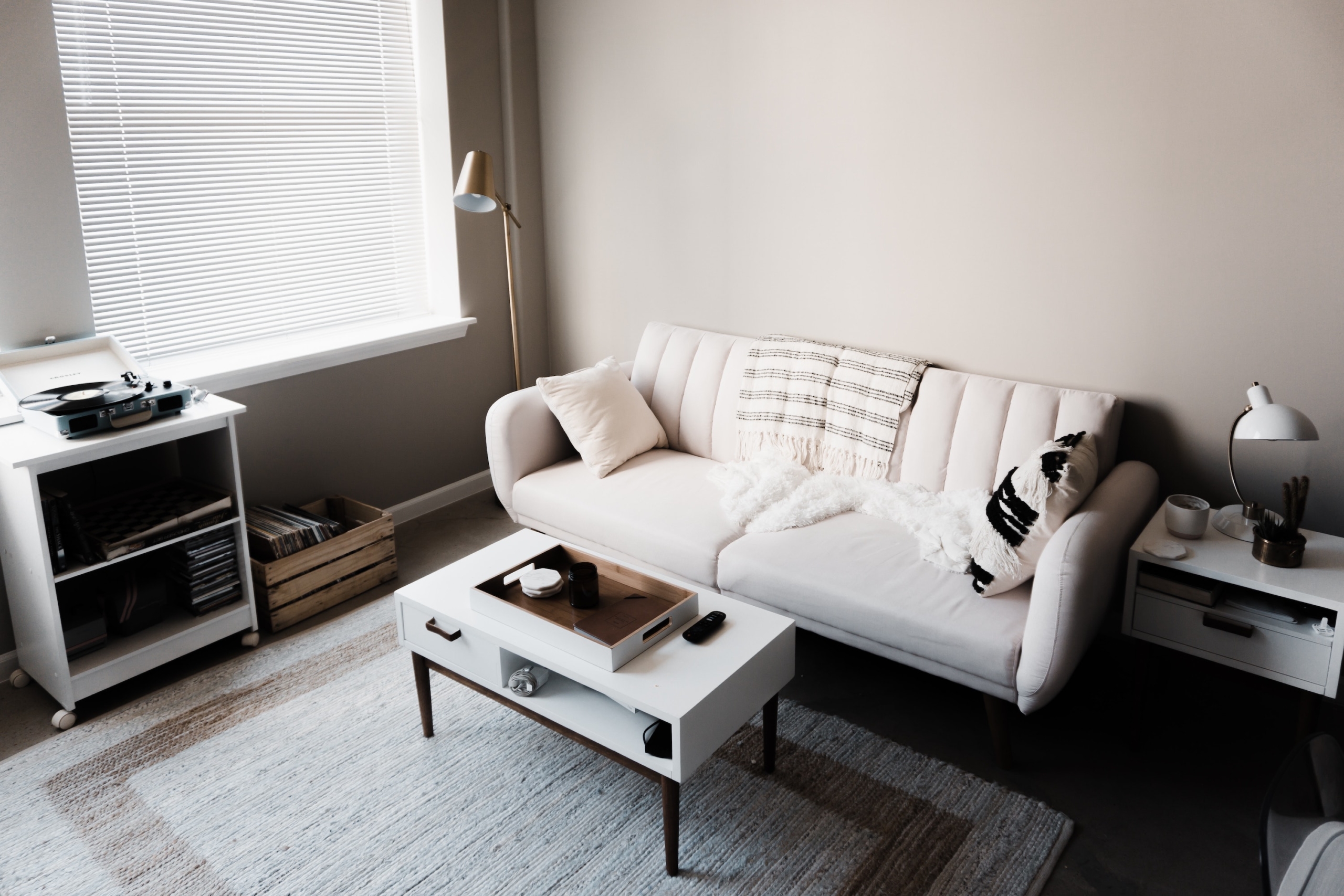 A white couch sits in a greyscale living room against a cream wall