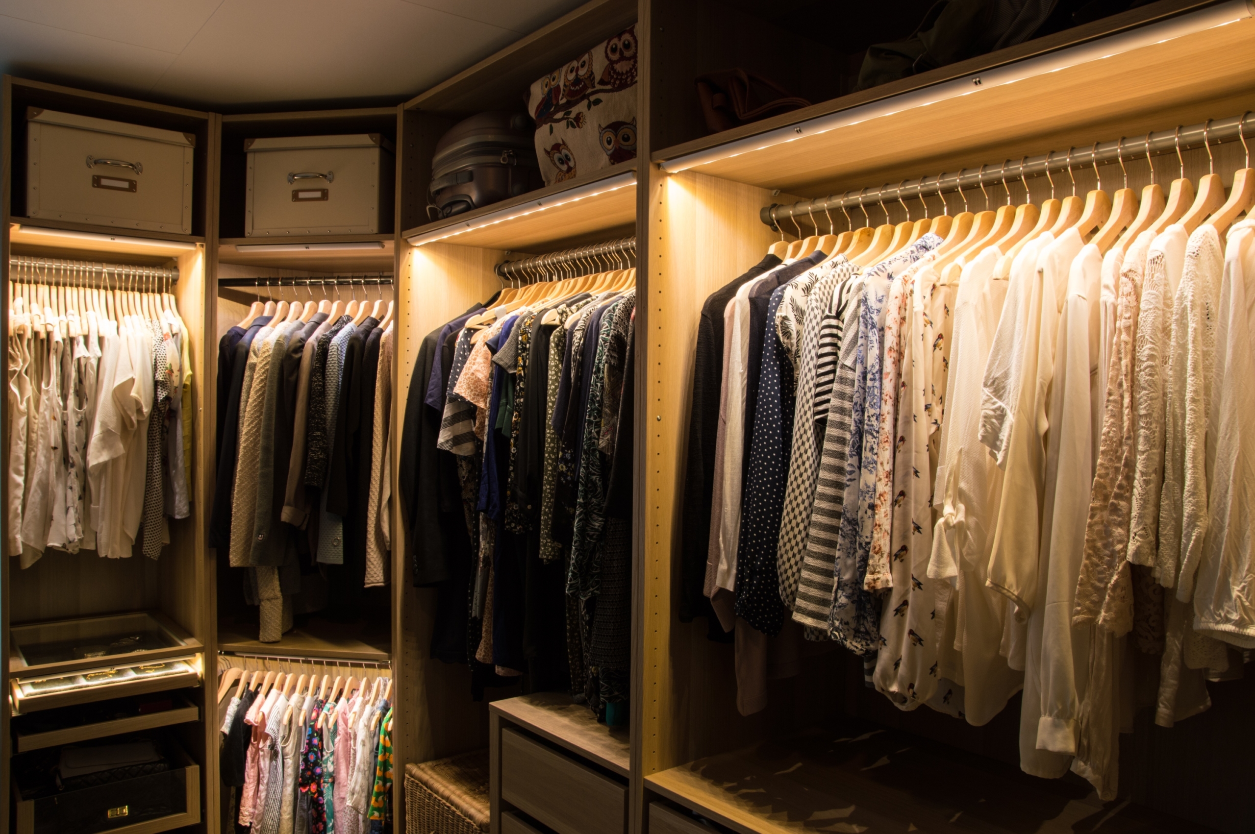 rows of clothes in a closet with lighting