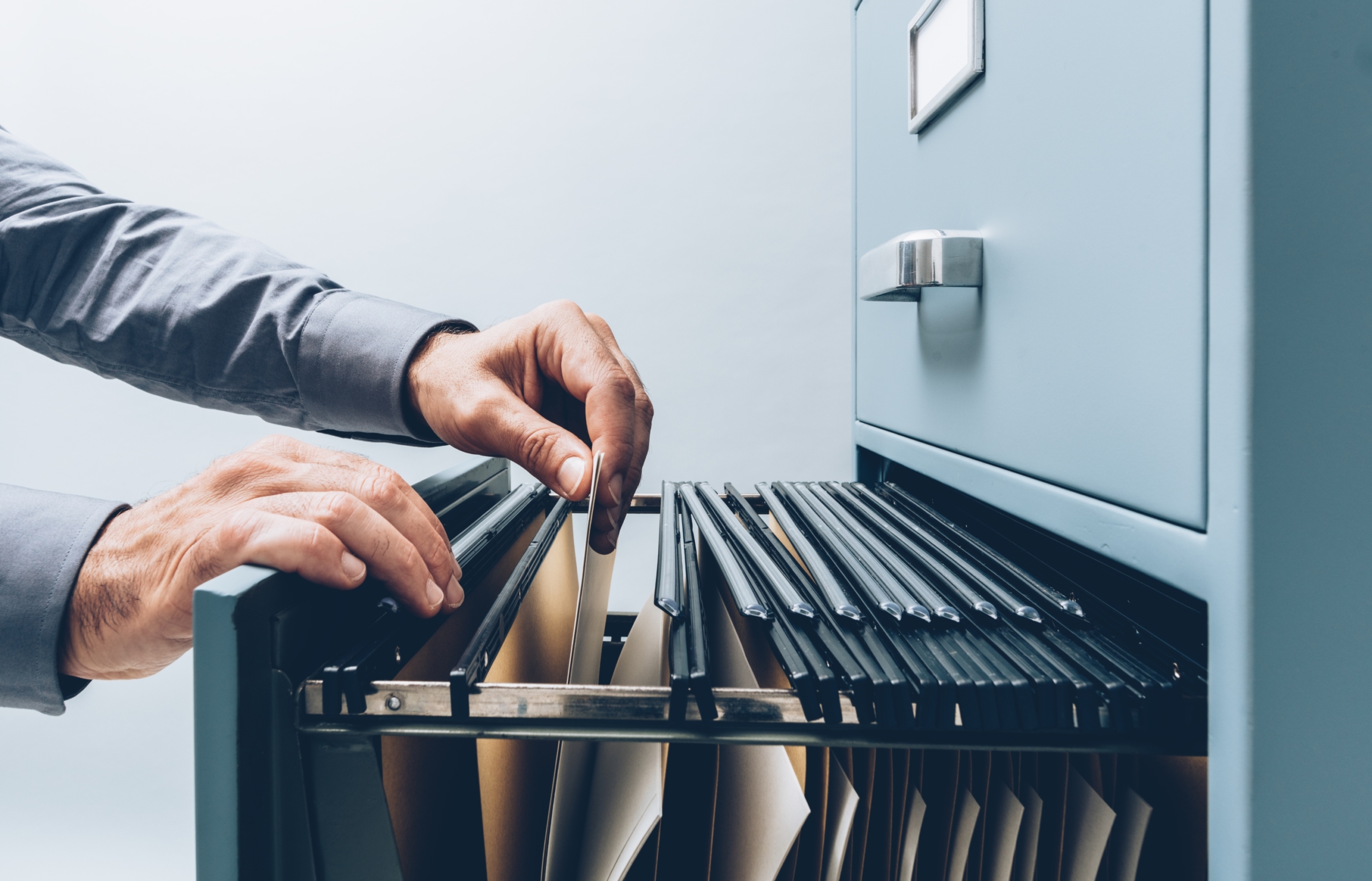 man filing papers in a filing cabinet