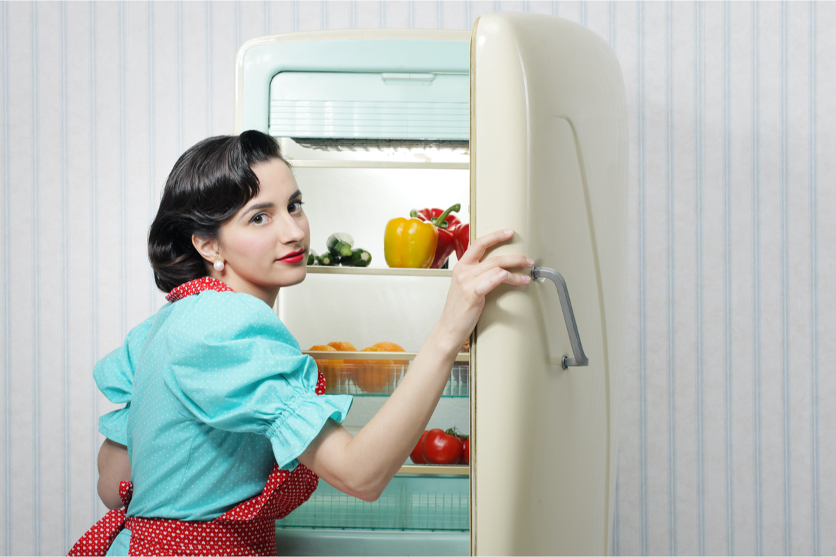 woman in 50s garb in front of vintage refrigerator