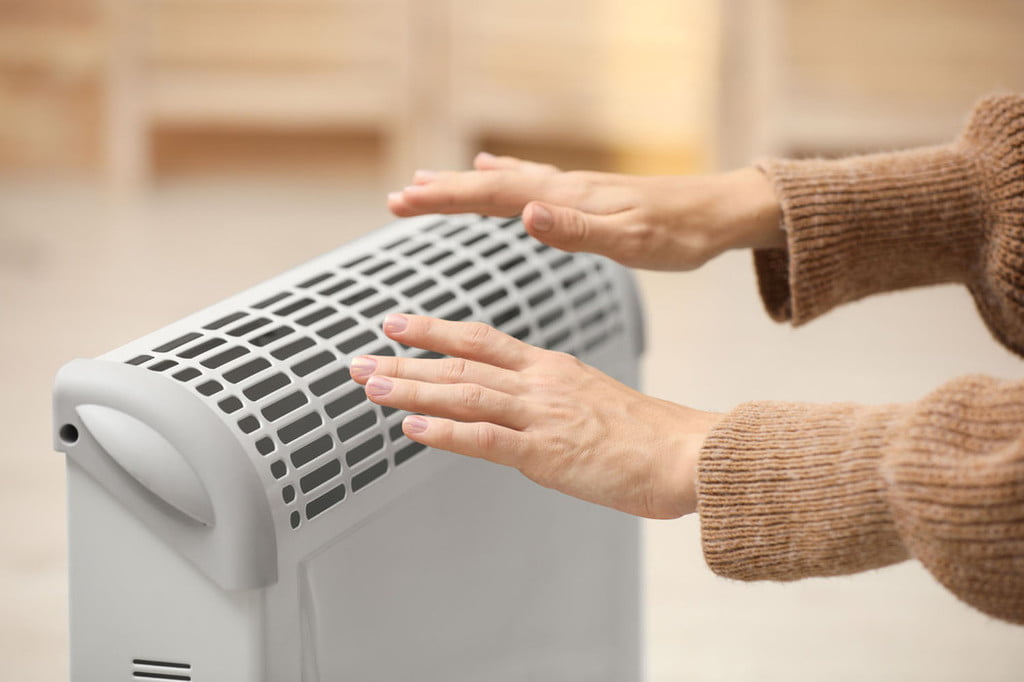 Person with hands over space heater