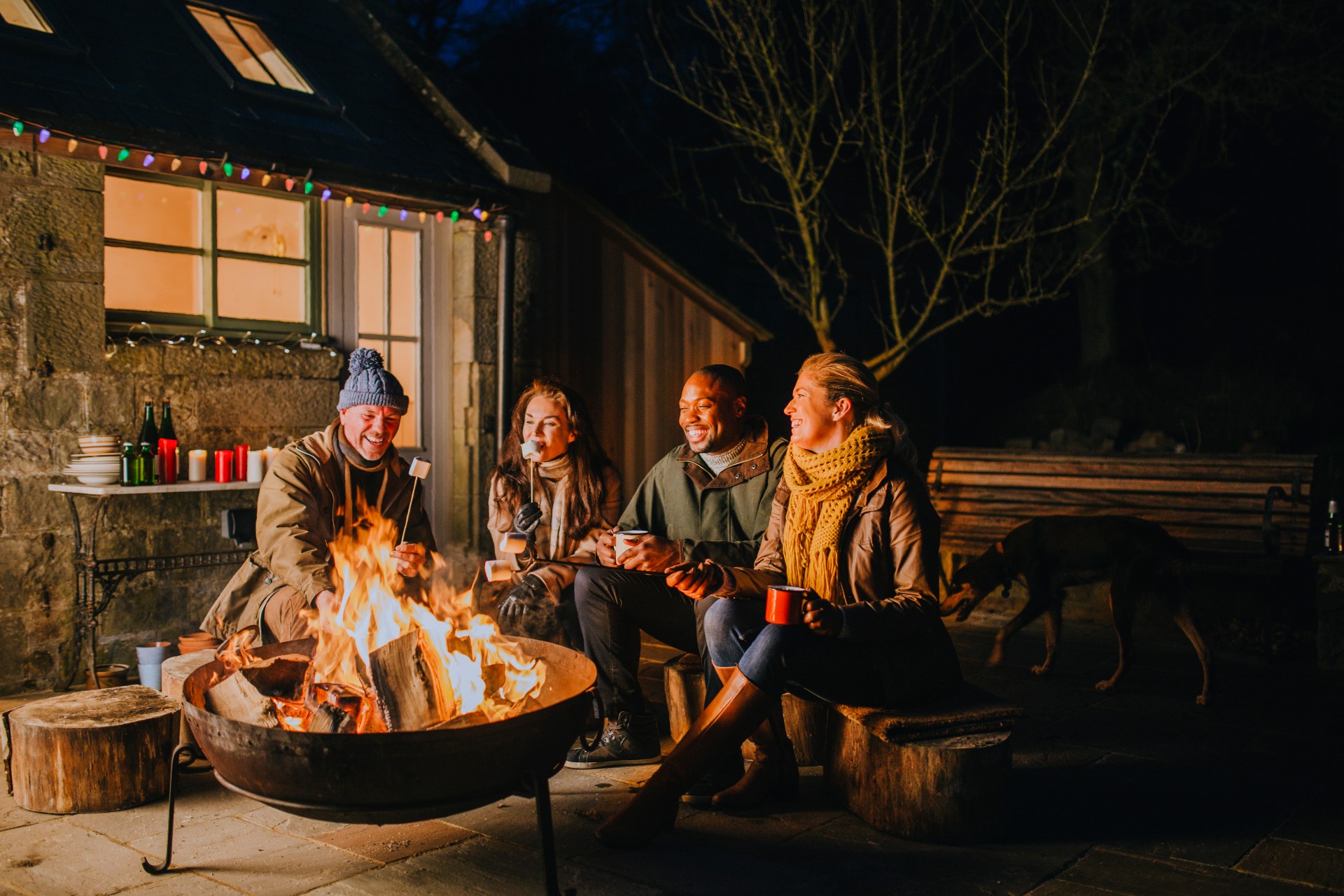 Two couples using a backyard firepit at night