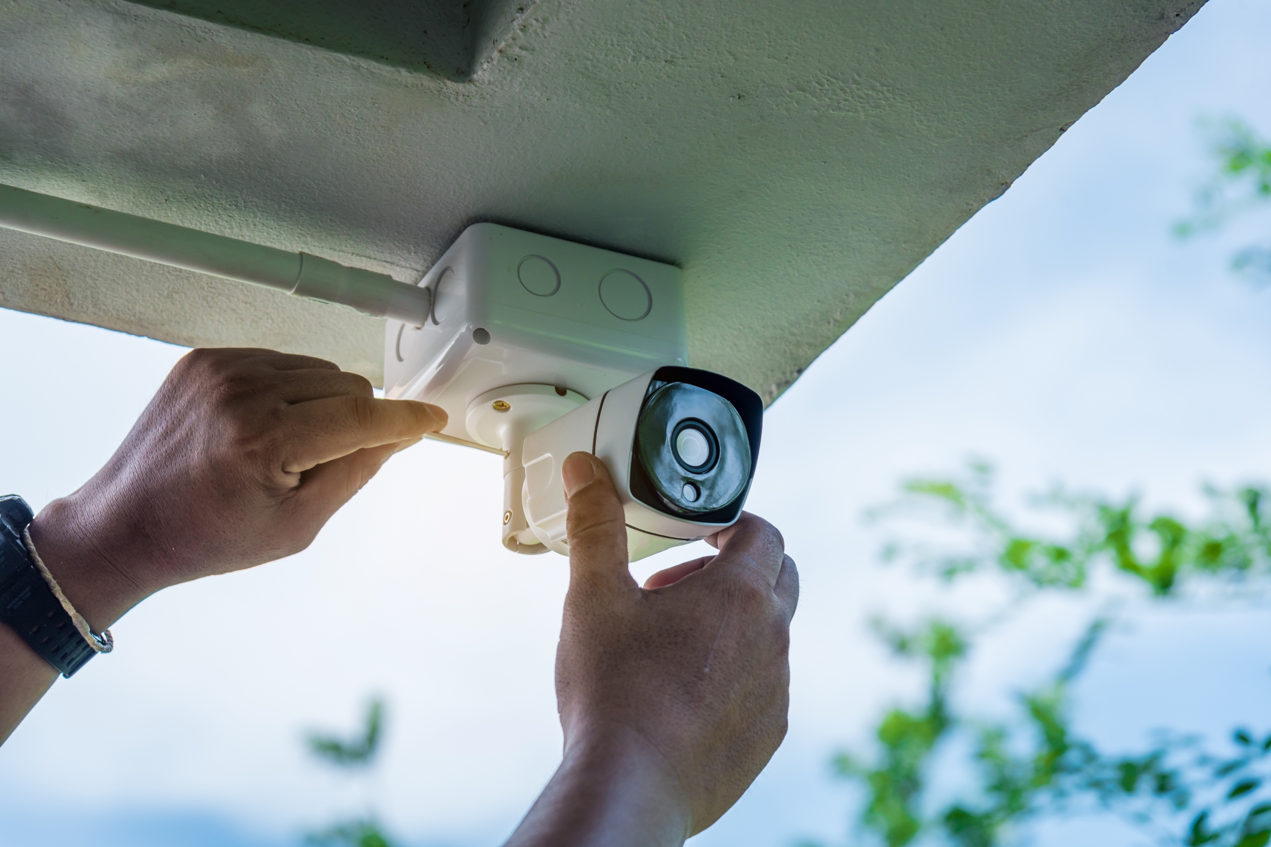 person installing wired home security camera
