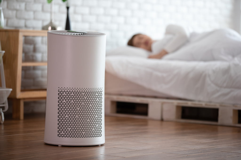 Person sleeping with an air purifier in a bedroom
