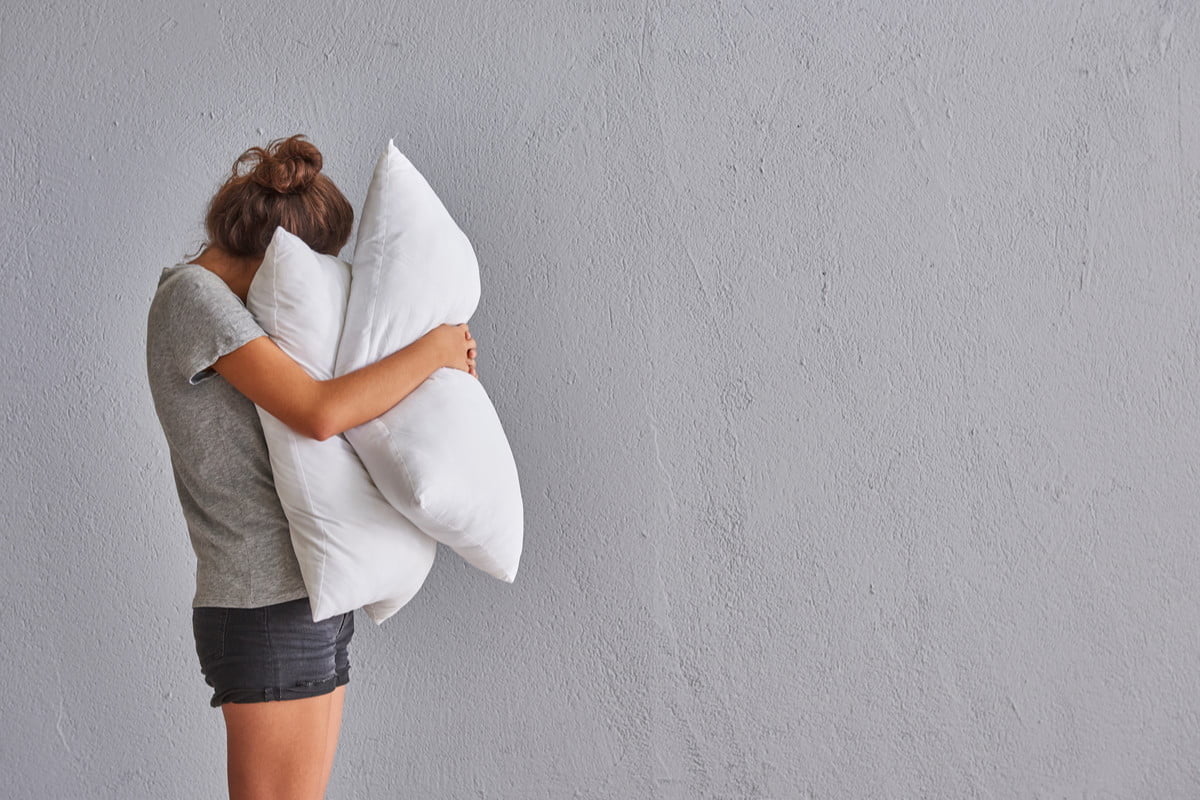 young woman hugging two pillows