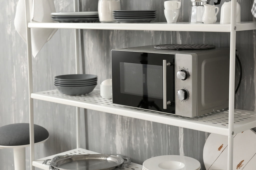 Microwave on a shelf with dishes