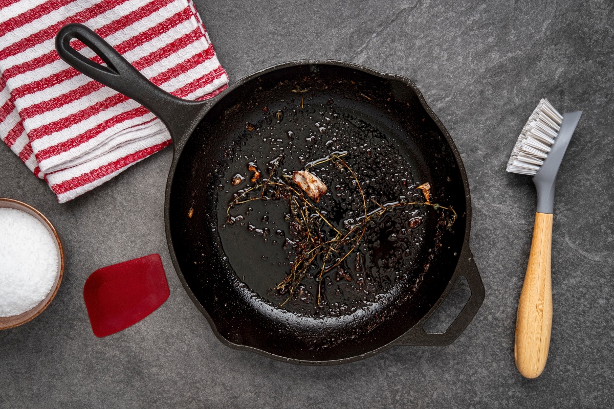 cleaning a dirty cast iron pan with brush