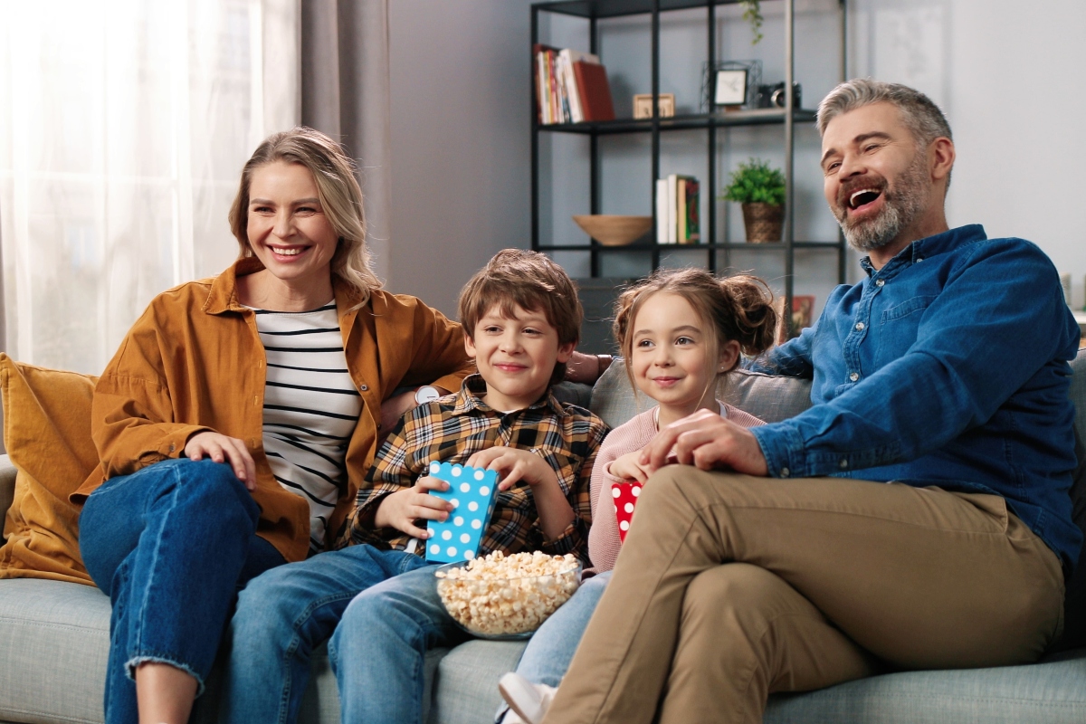 family sitting on couch watching tv together