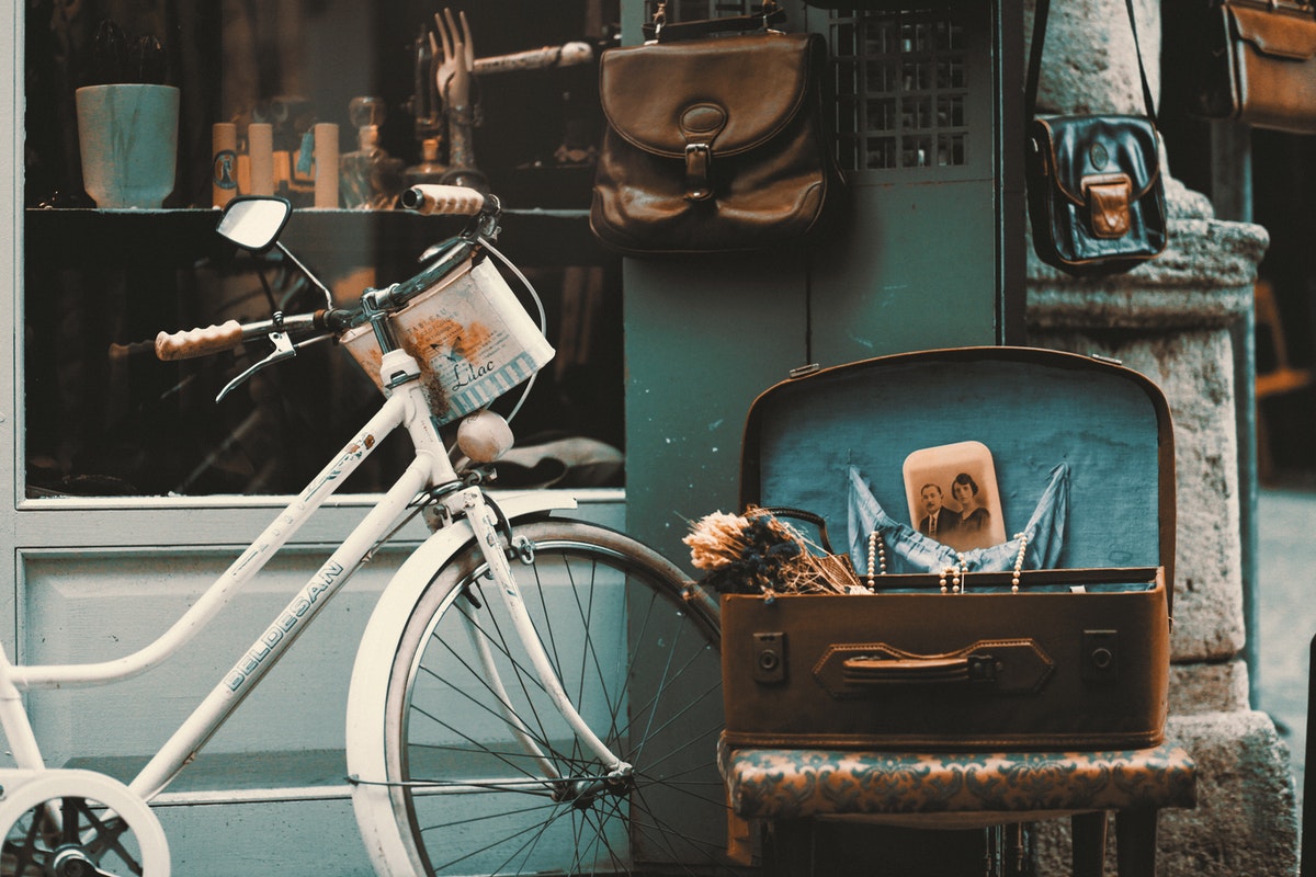 A vintage set up with an old bike and an old suitcase holding items.