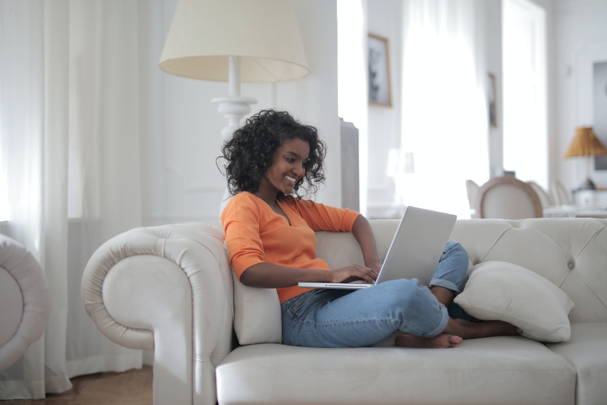 woman sitting on white couch with a laptop