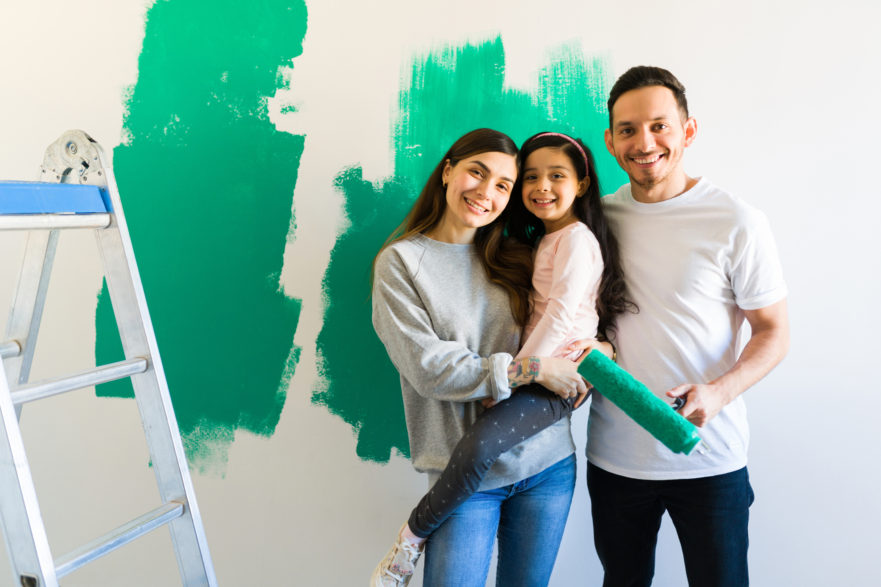 Family poses beside green painted wall