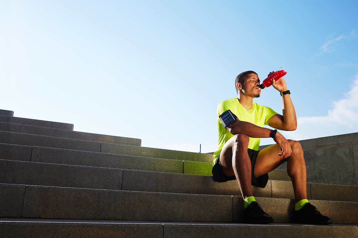 Runner seated on the steps drinking a sports drink