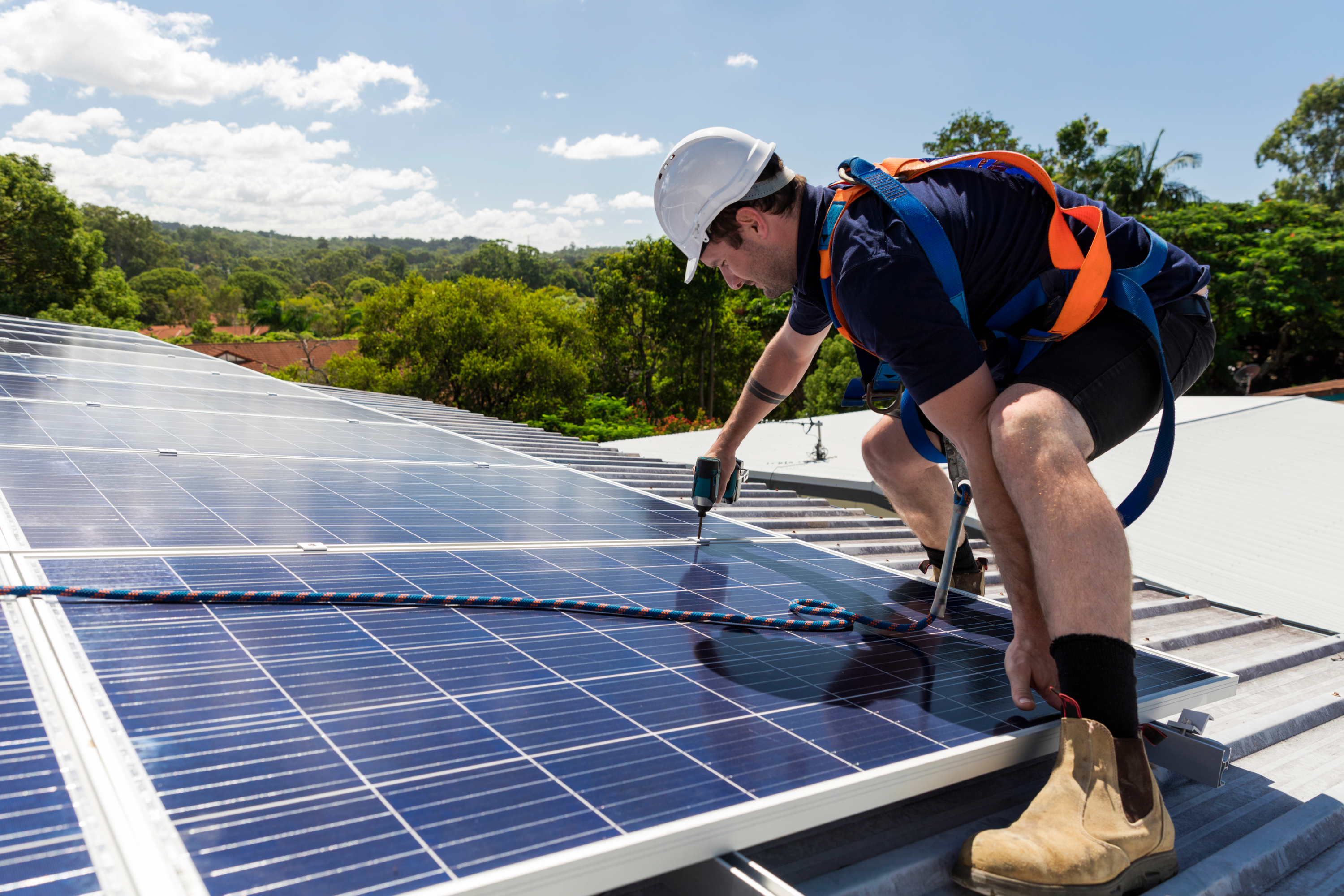 Worker installing solar panels on roof