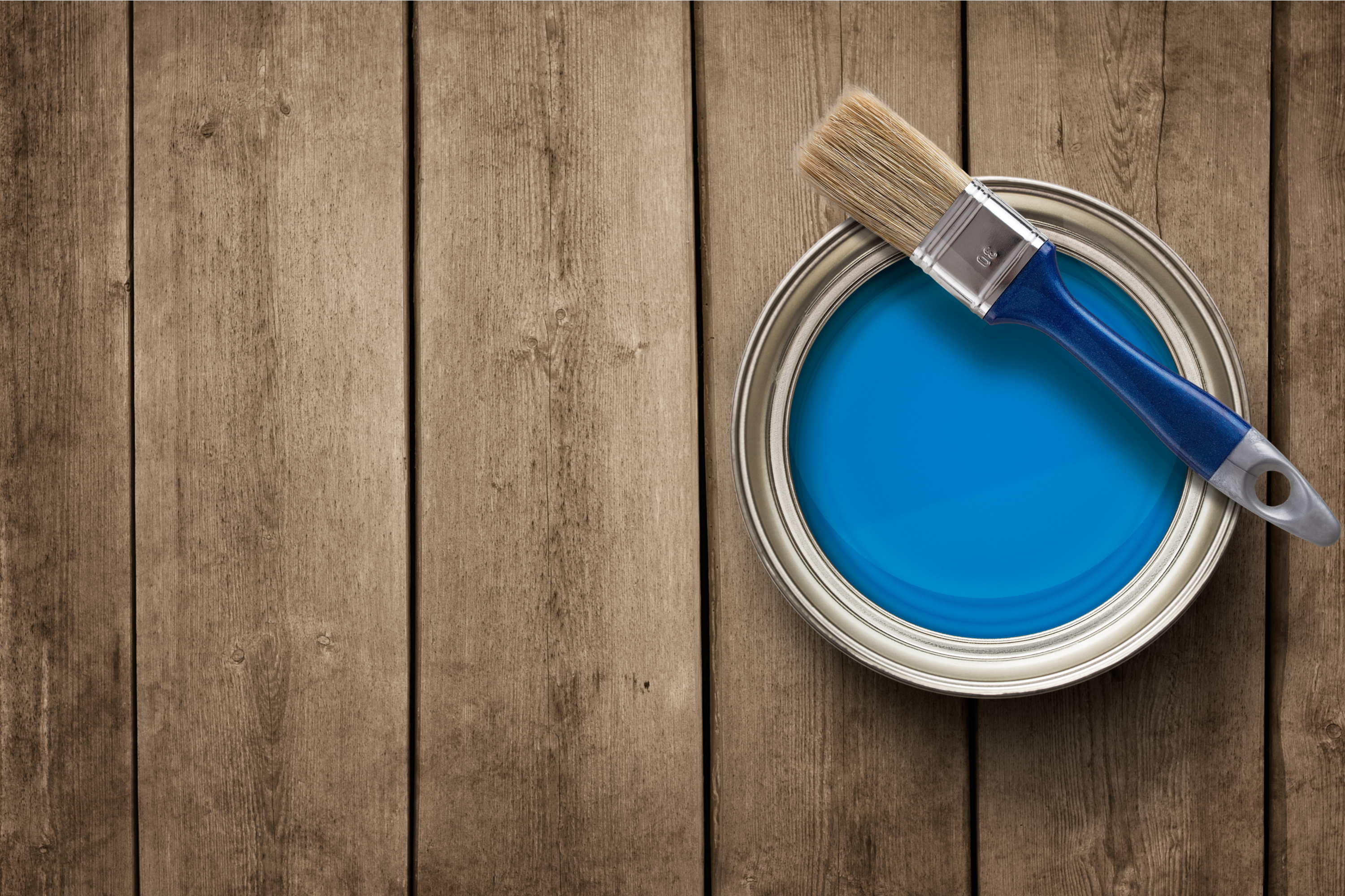Small blue paint can with paint brush set on top.