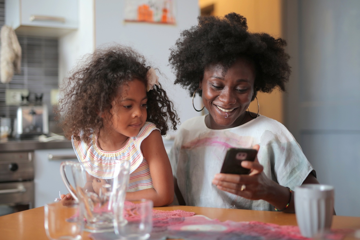 young girl and her mom using iphone while cooking