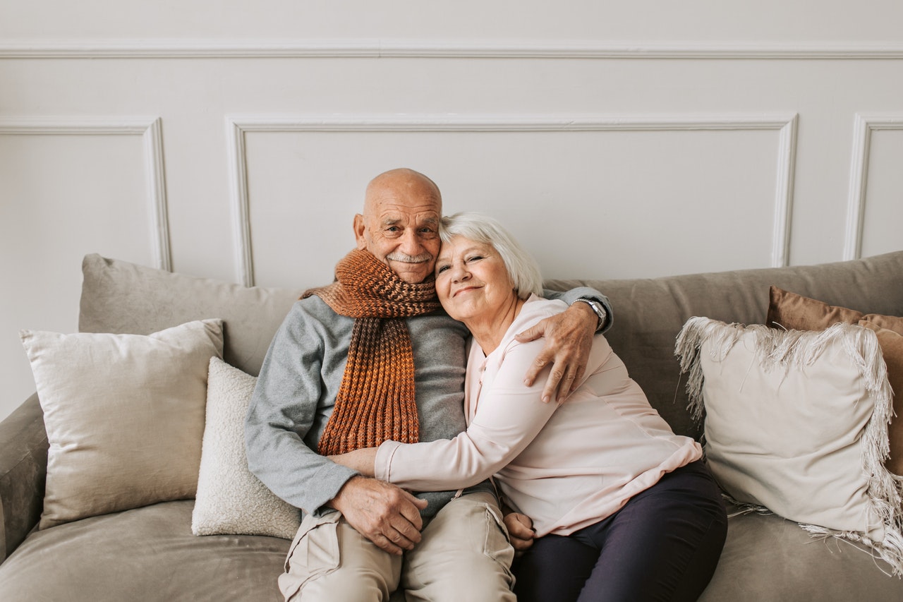 elderly couple sitting on gray couch