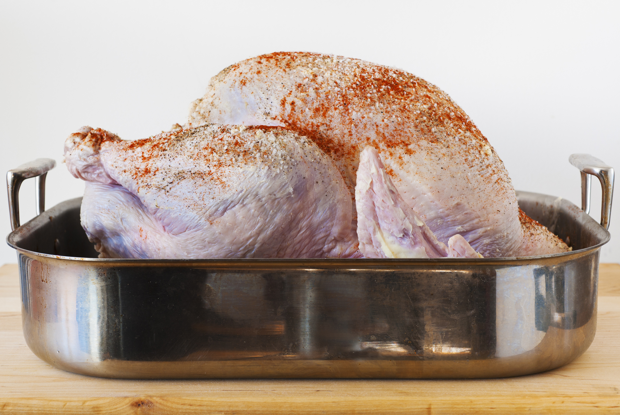 raw turkey with seasonings in a roasting pan
