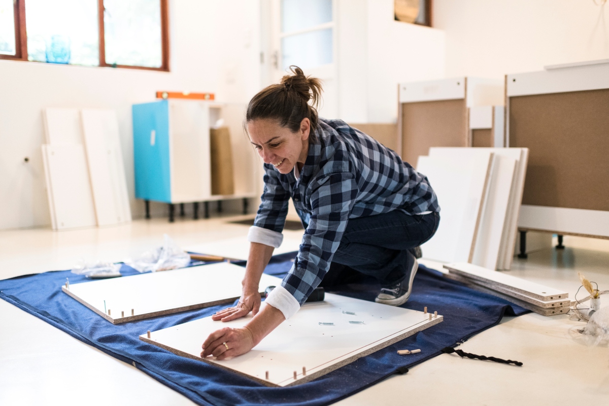 Woman placing kitchen cabinets in remodel