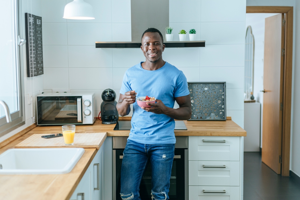 Man eating food in a kitchen with blue walls
