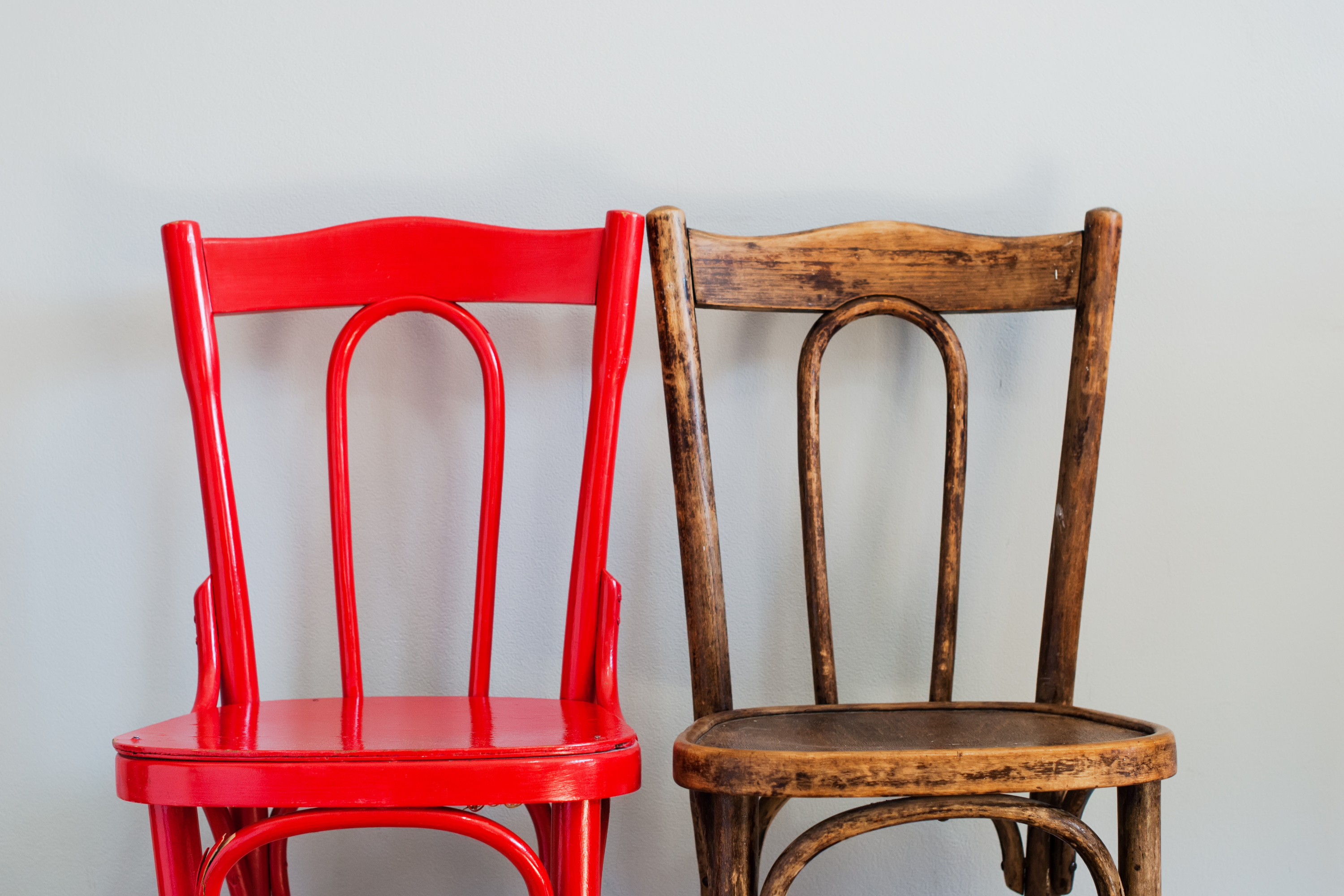 Two wooden chairs next to each other: one is painted red and one is natural wood