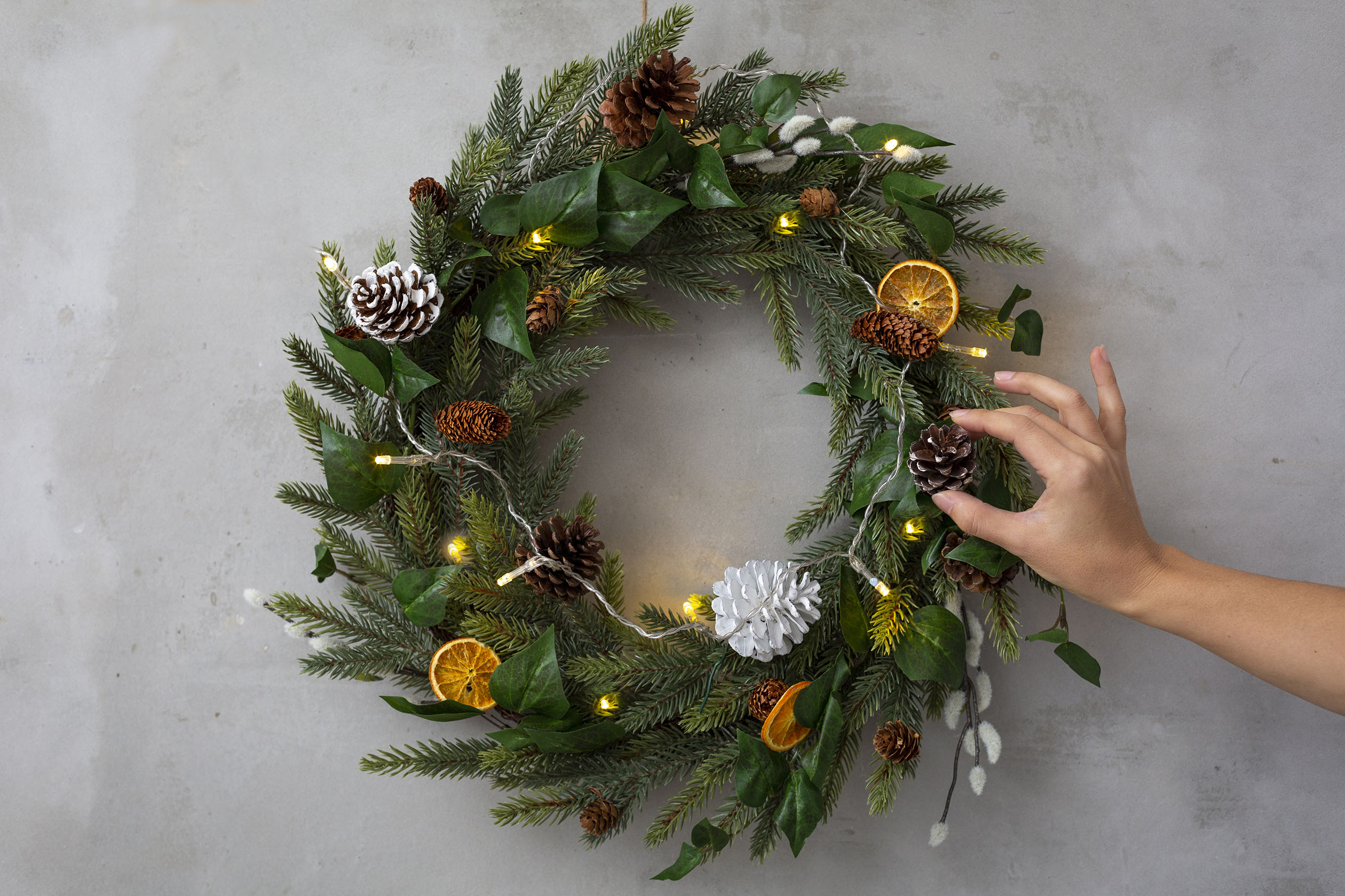 Person adjusting a winter wreath