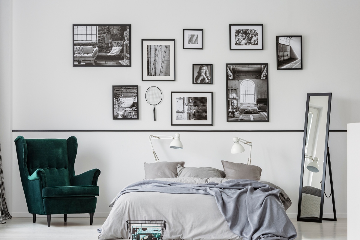 Gallery wall above bed with black and white frames and small mirror