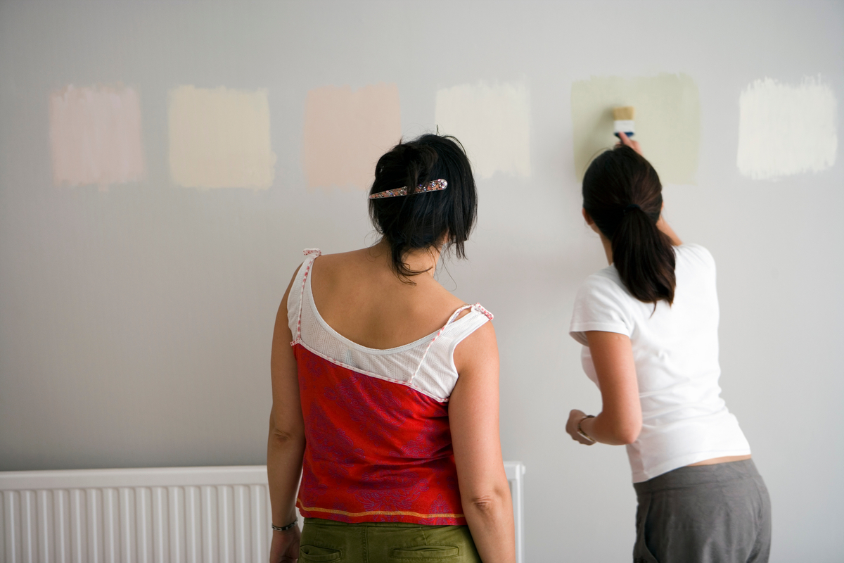 two women using paint samples on wall