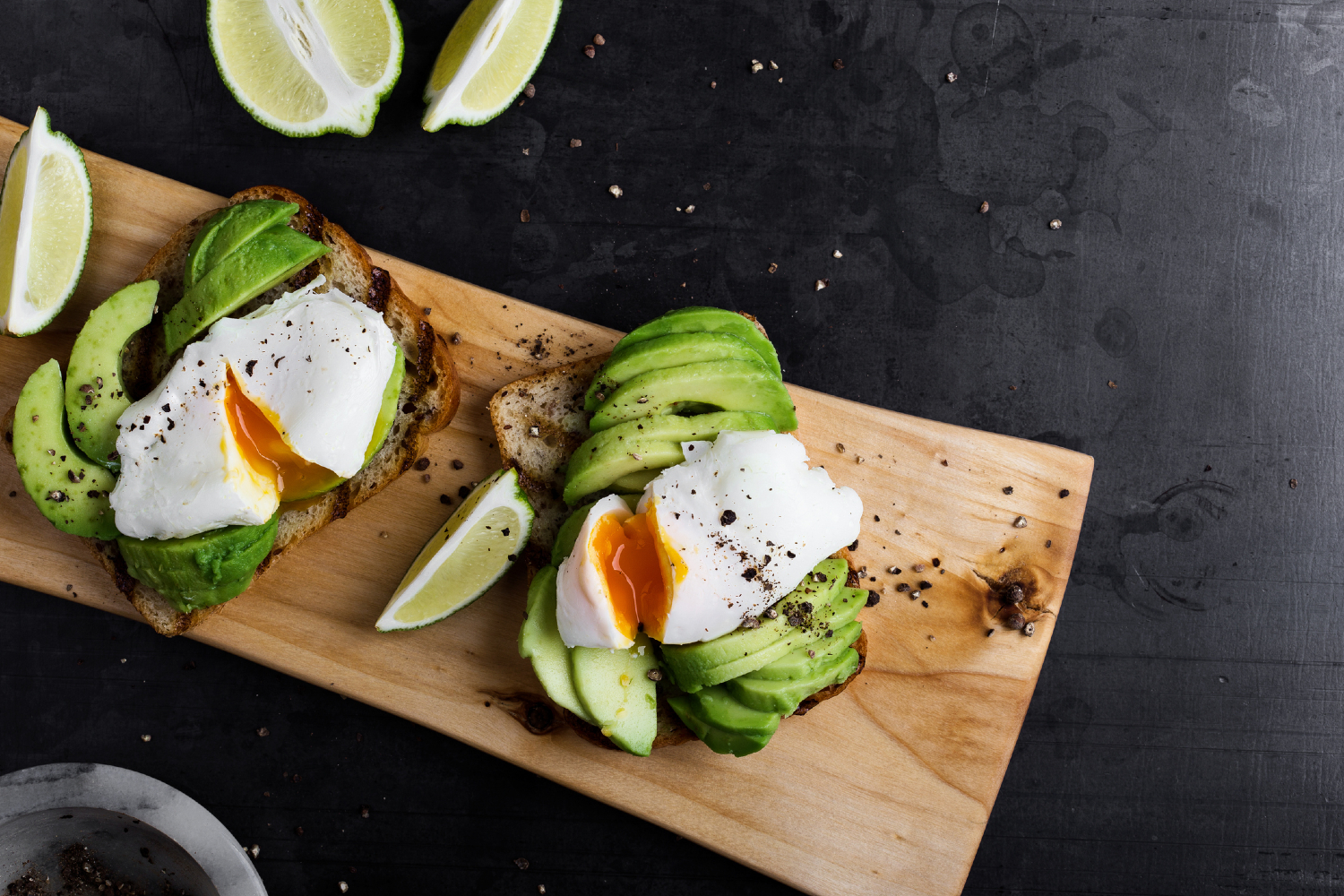 Avocado toast with egg on cutting board.