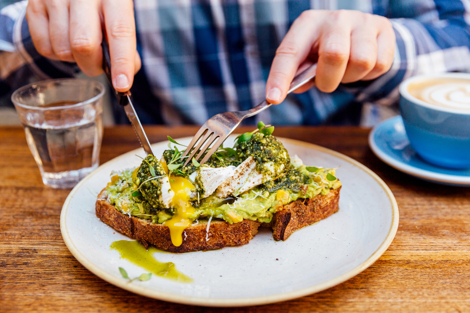 Man cutting into avocado toast with egg