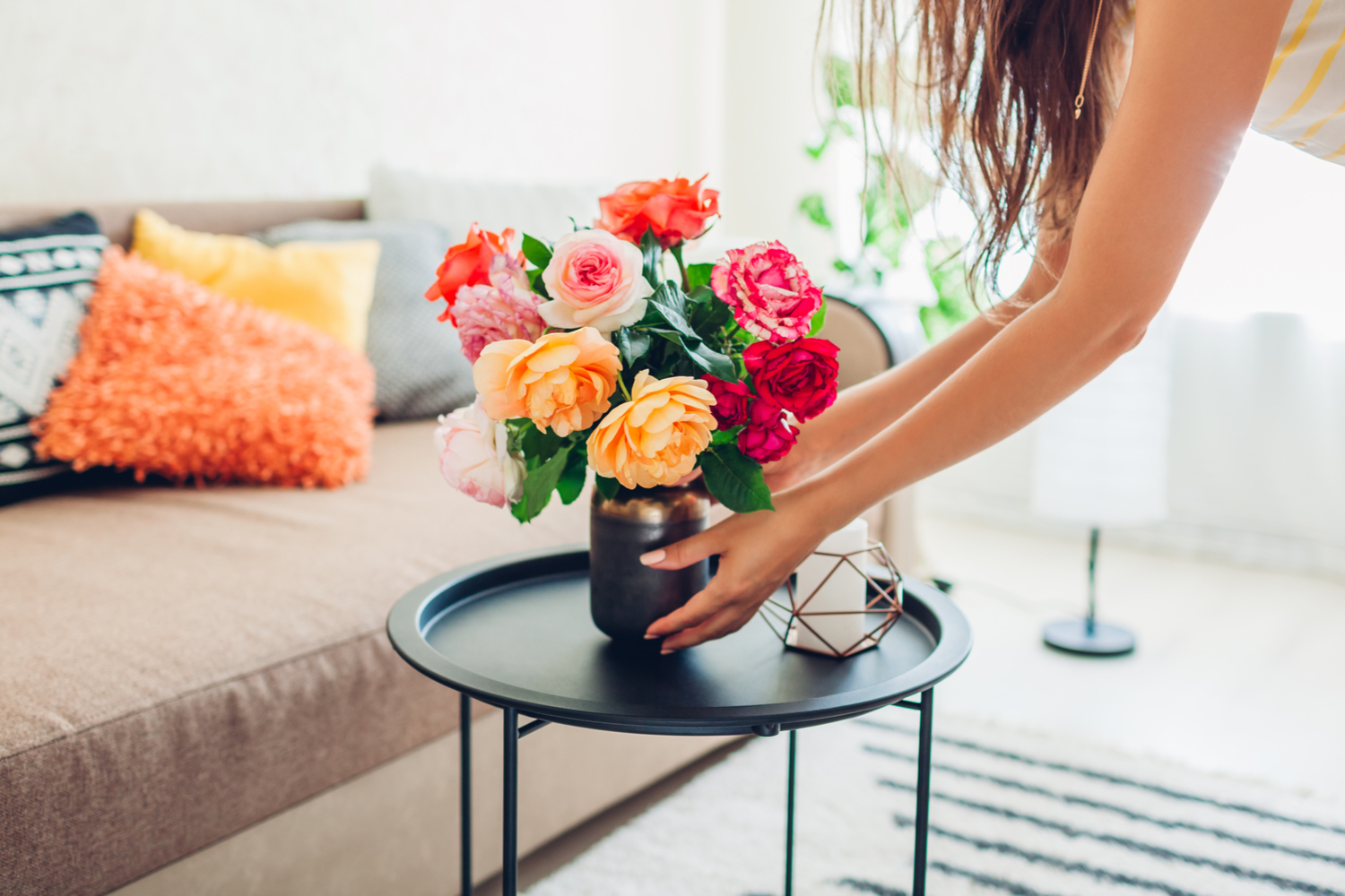 Person placing flowers in a vase on a coffee table