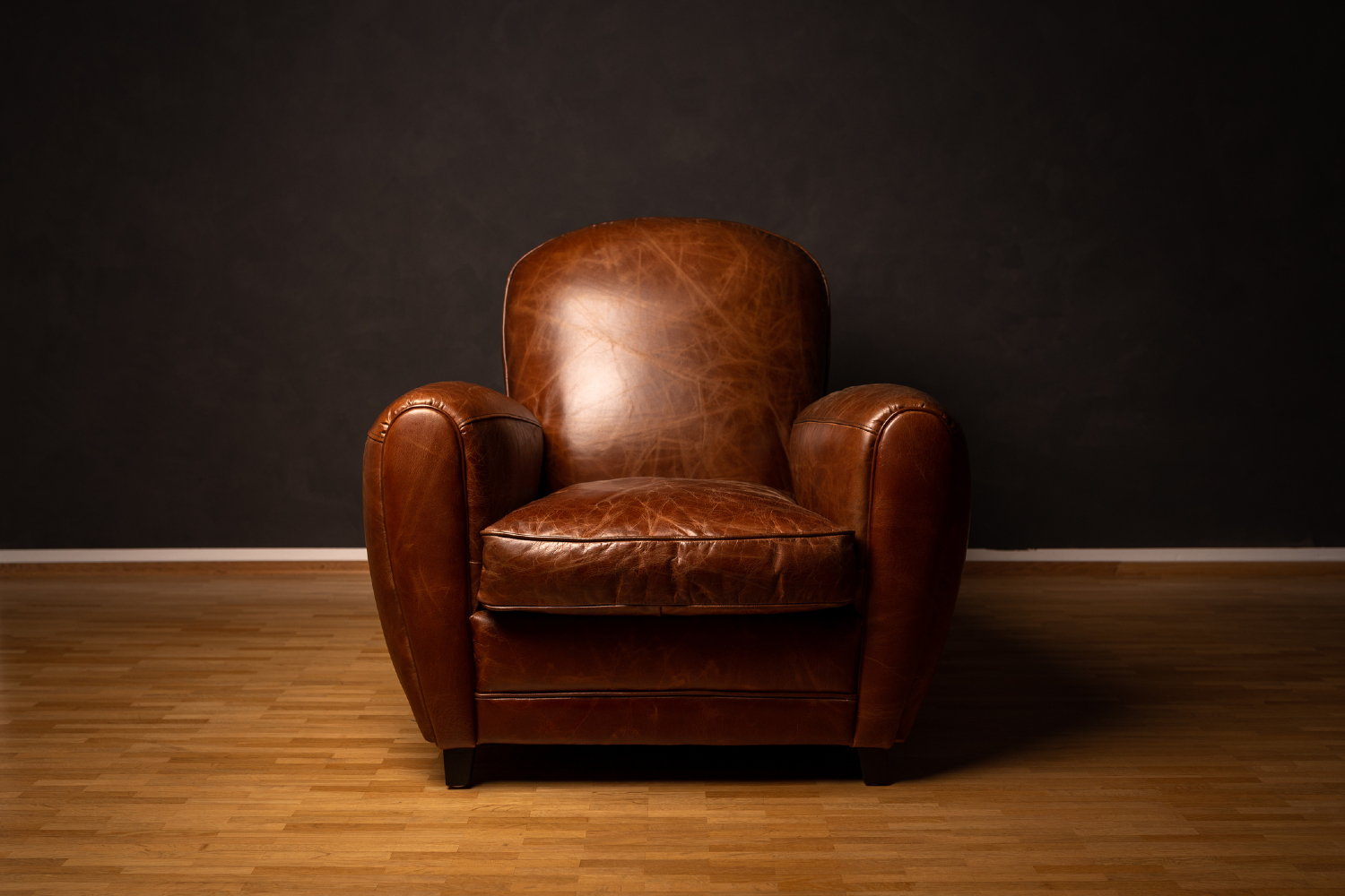 Brown armchair with black walls.