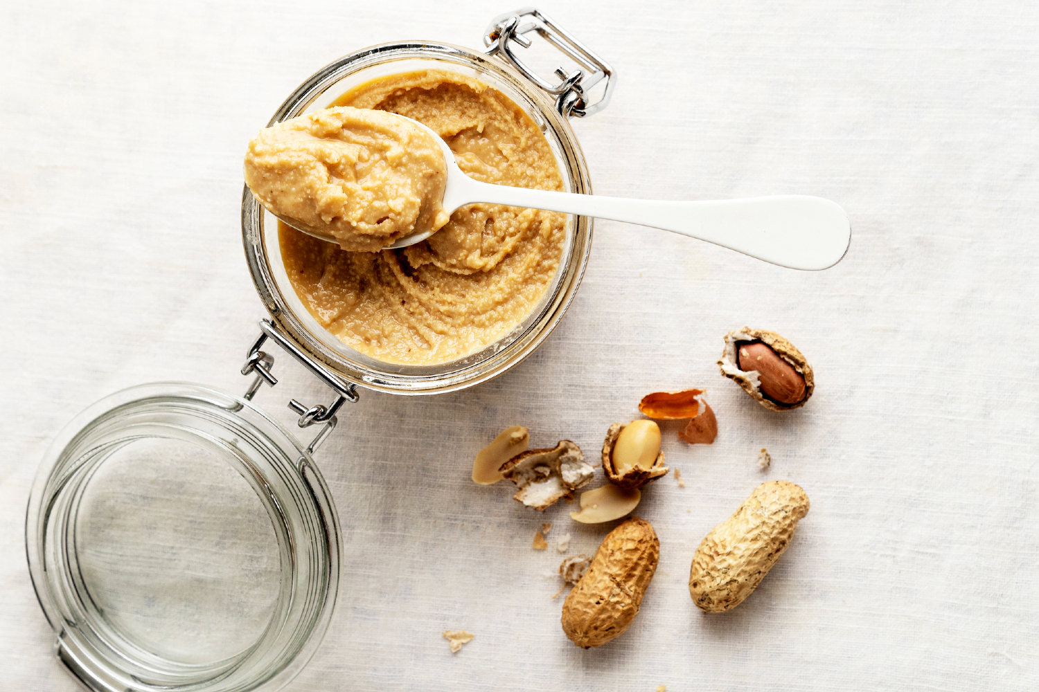 Homemade peanut butter in jar with peanuts next to it.