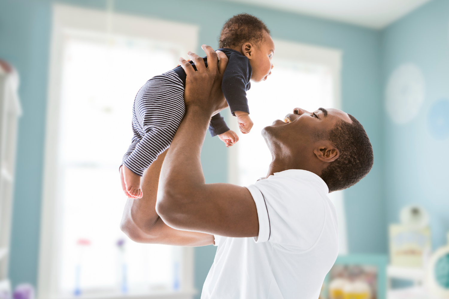 Man with baby in blue nursery.