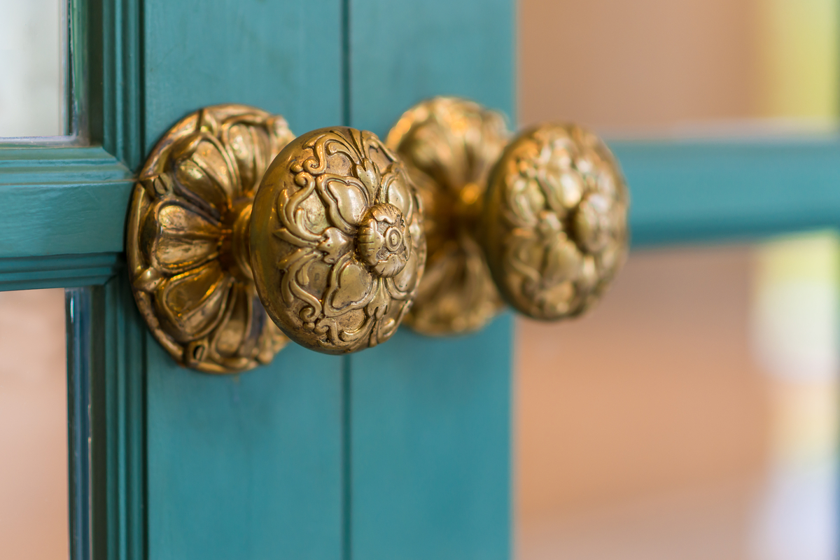 Brass handles on teal cabinet doors