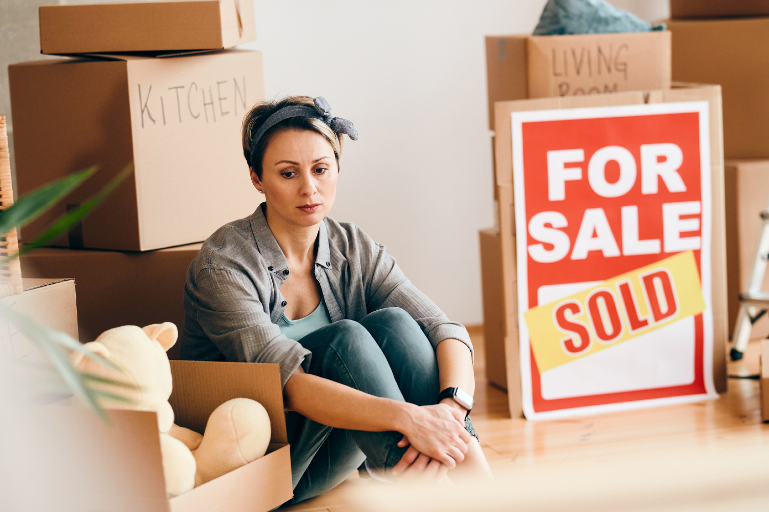 Woman looking sad with for sale sign