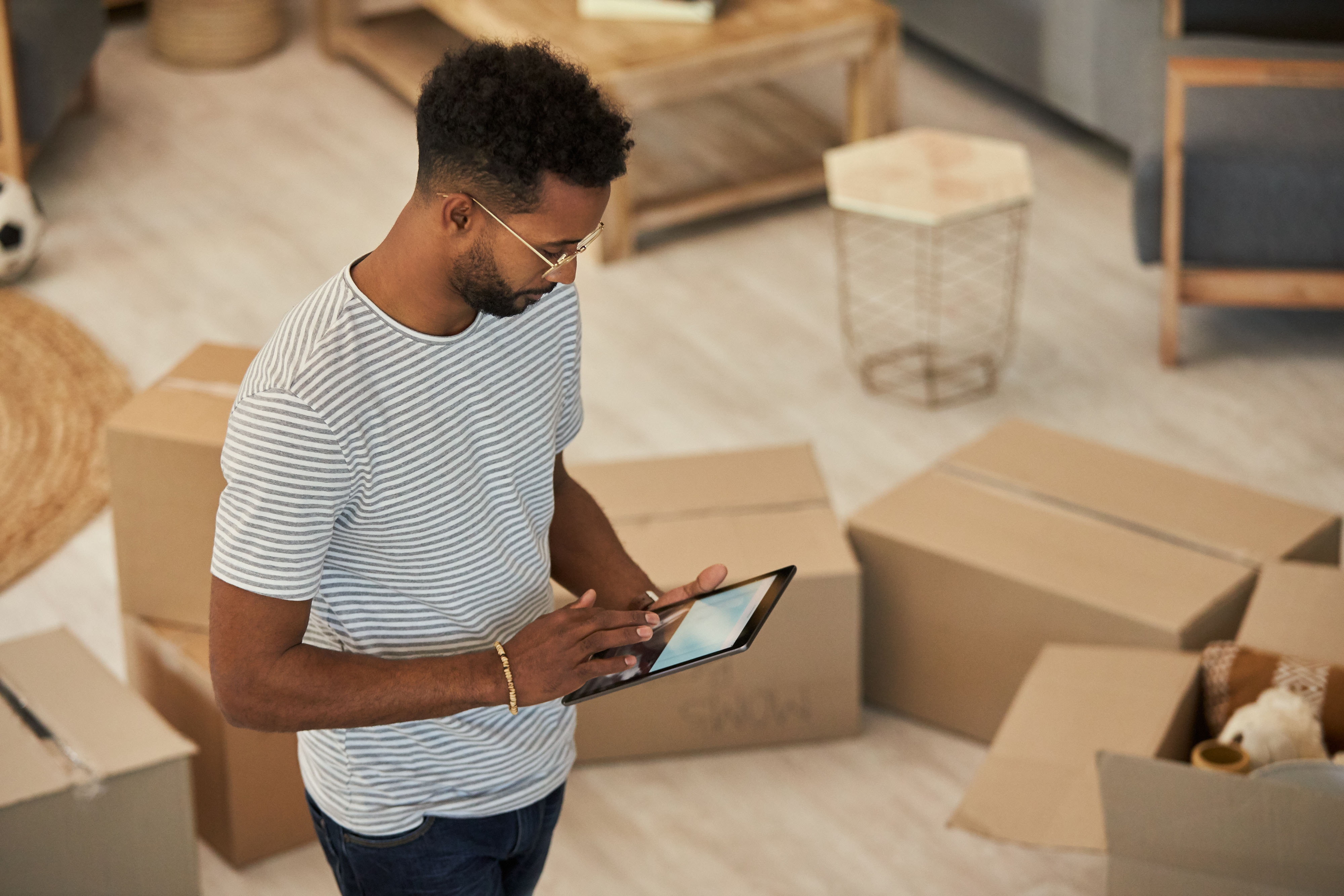Man on iPad surrounded by moving boxes