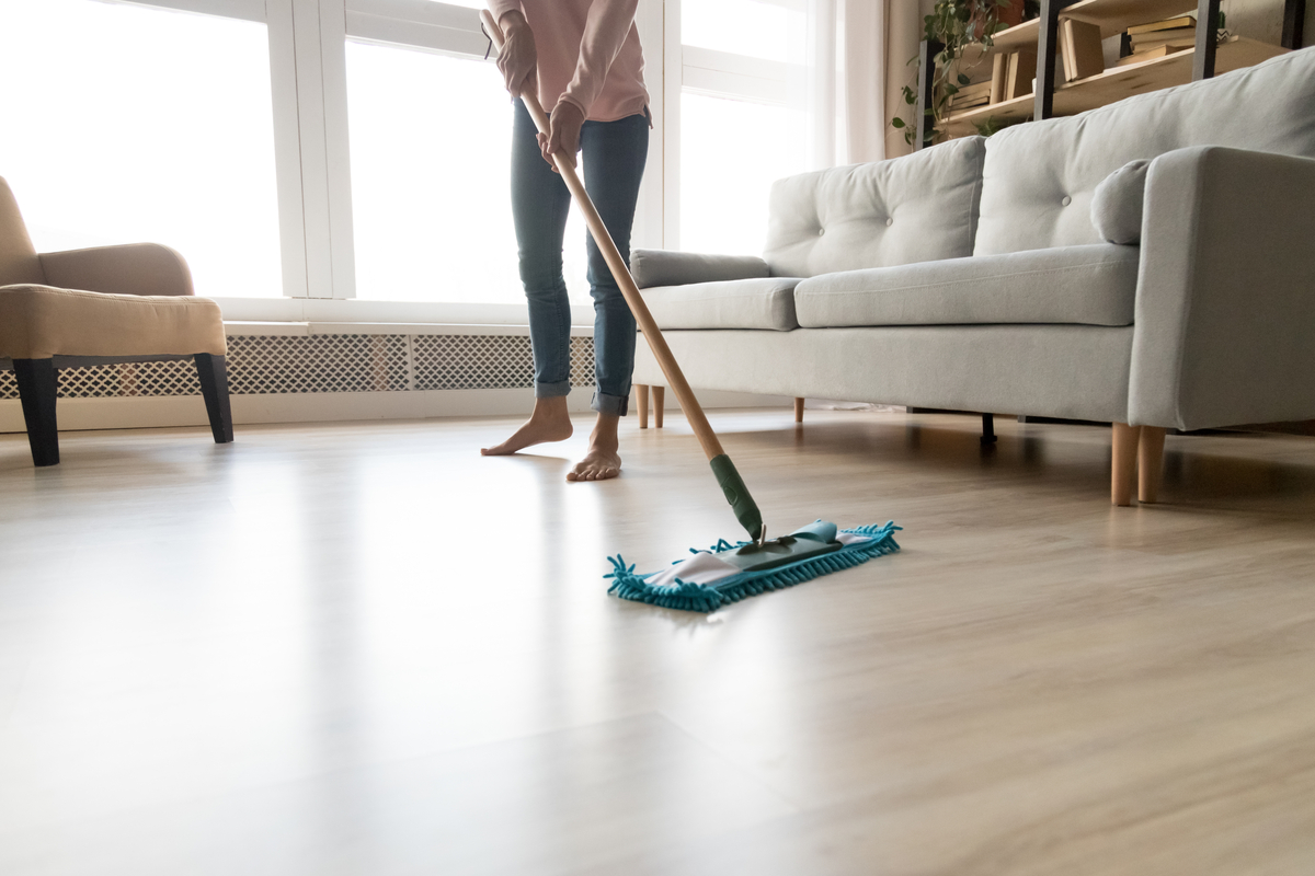 Woman with bare feet cleaning laminate floor with swiffer style mop